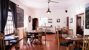 Un comedor con mesas y sillas de madera, un menú en una pizarra y un ventilador de techo.