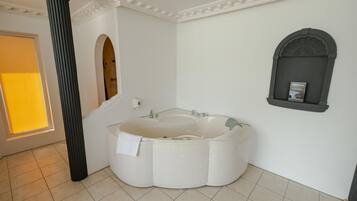 Een moderne badkamer met een vrijstaand bad, een grote spiegel en een decoratieve kolom.