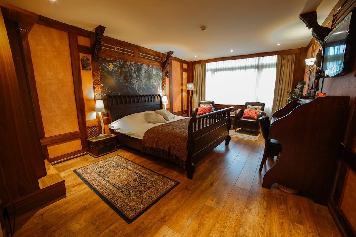 A spacious bedroom with a large bed, a wooden desk, and a television.