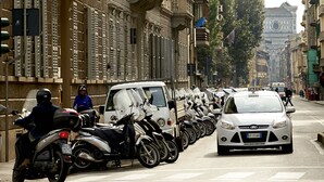 Una calle bordeada por motocicletas estacionadas y un taxi.