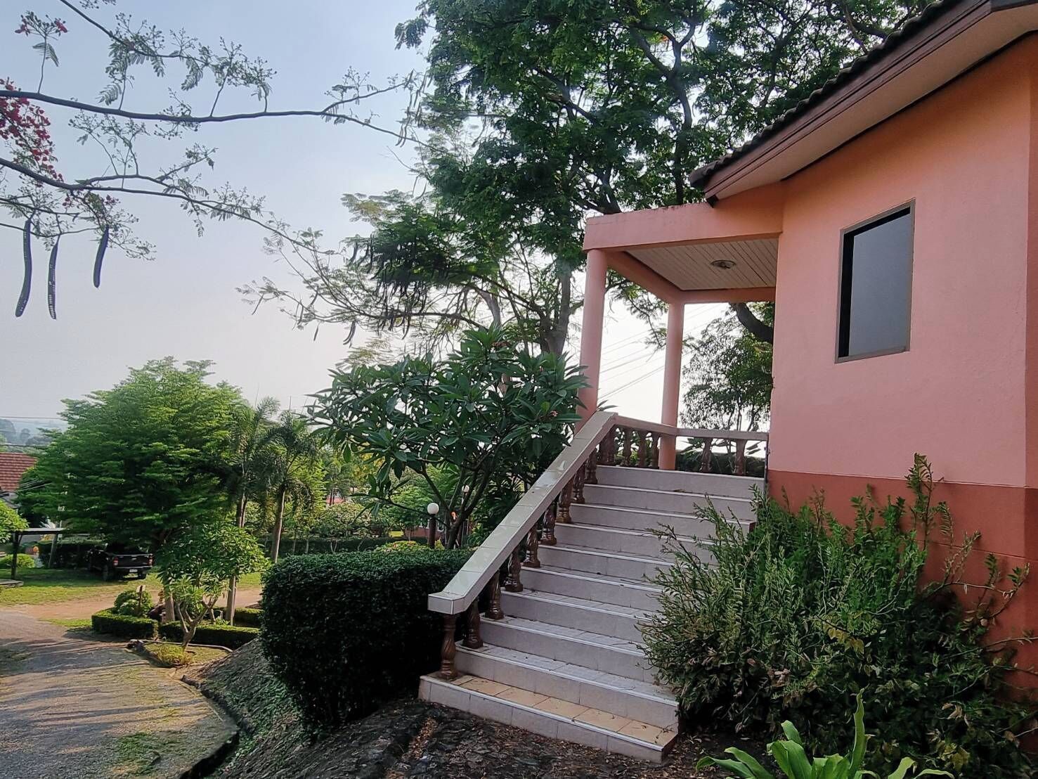 Un edificio rosa con una escalera que conduce a un porche cubierto.