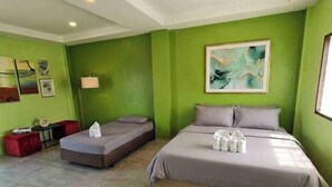 Una habitación con cama, sofá, lámpara de pie y obras de arte en las paredes.