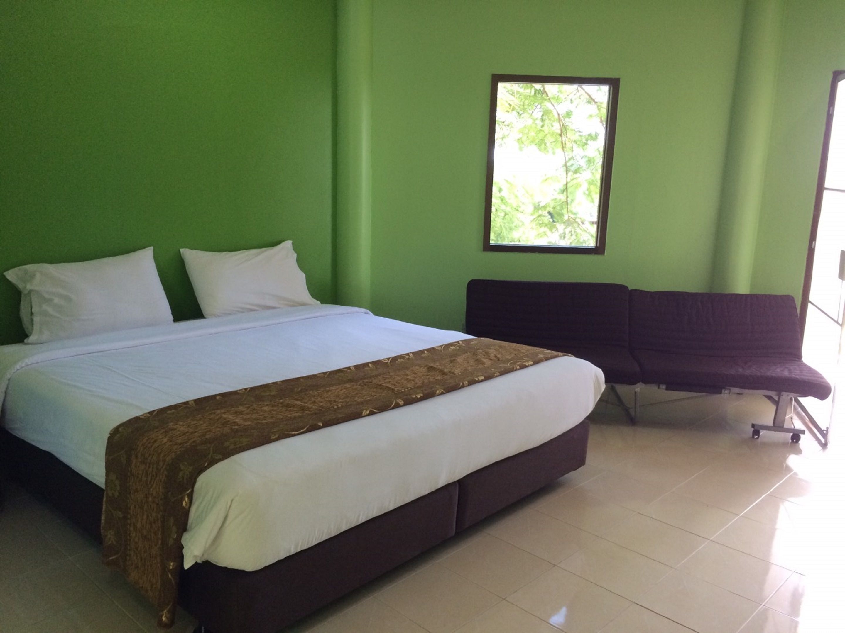 Una habitación con una cama, un banco y una ventana.