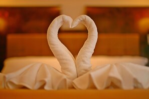 A bed with a white blanket and a towel arranged in a heart shape. - Lotusland Resort (Pattaya)