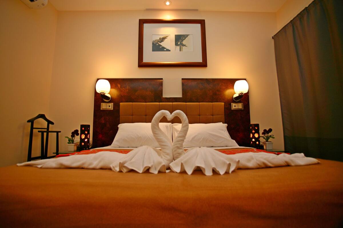 Ein Hotelzimmer mit einem Bett, einem gerahmten Bild an der Wand und zwei Wandleuchten.