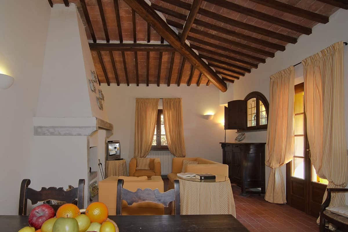 Ein gemütliches Wohnzimmer mit Kamin, einer Couch und einem Esstisch mit Obst.