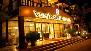 The exterior of Venus Suite Hotel with a well-lit entrance, large windows, and potted plants. - Venus Suite Hotel (Denizli)