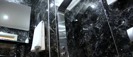 A modern bathroom with a black marble wall, a large mirror, a shower, and a towel rack.