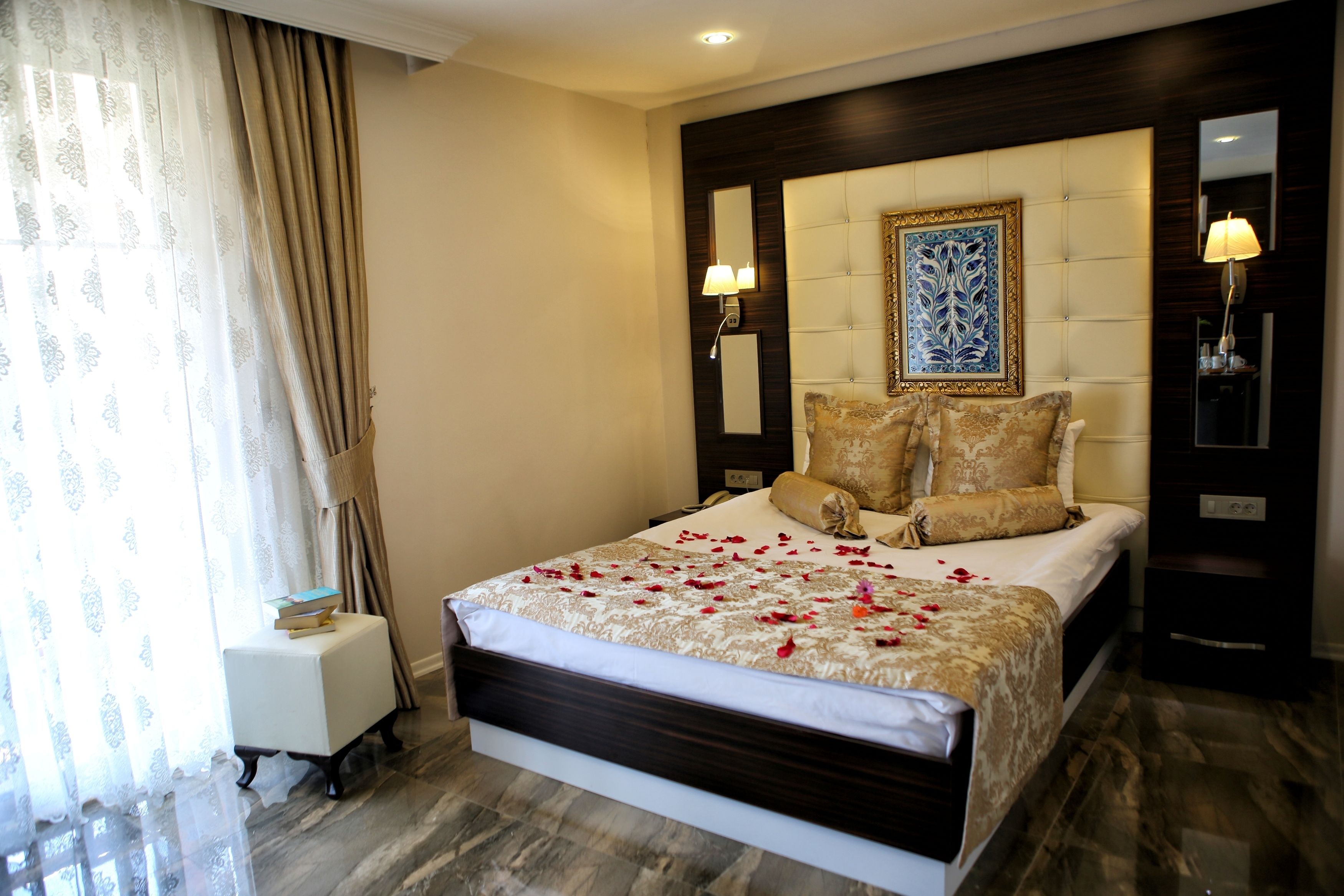 A hotel room with a large bed, a nightstand, a lamp, and a decorative headboard.