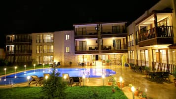 A hotel with a swimming pool, outdoor seating, and multiple balconies.