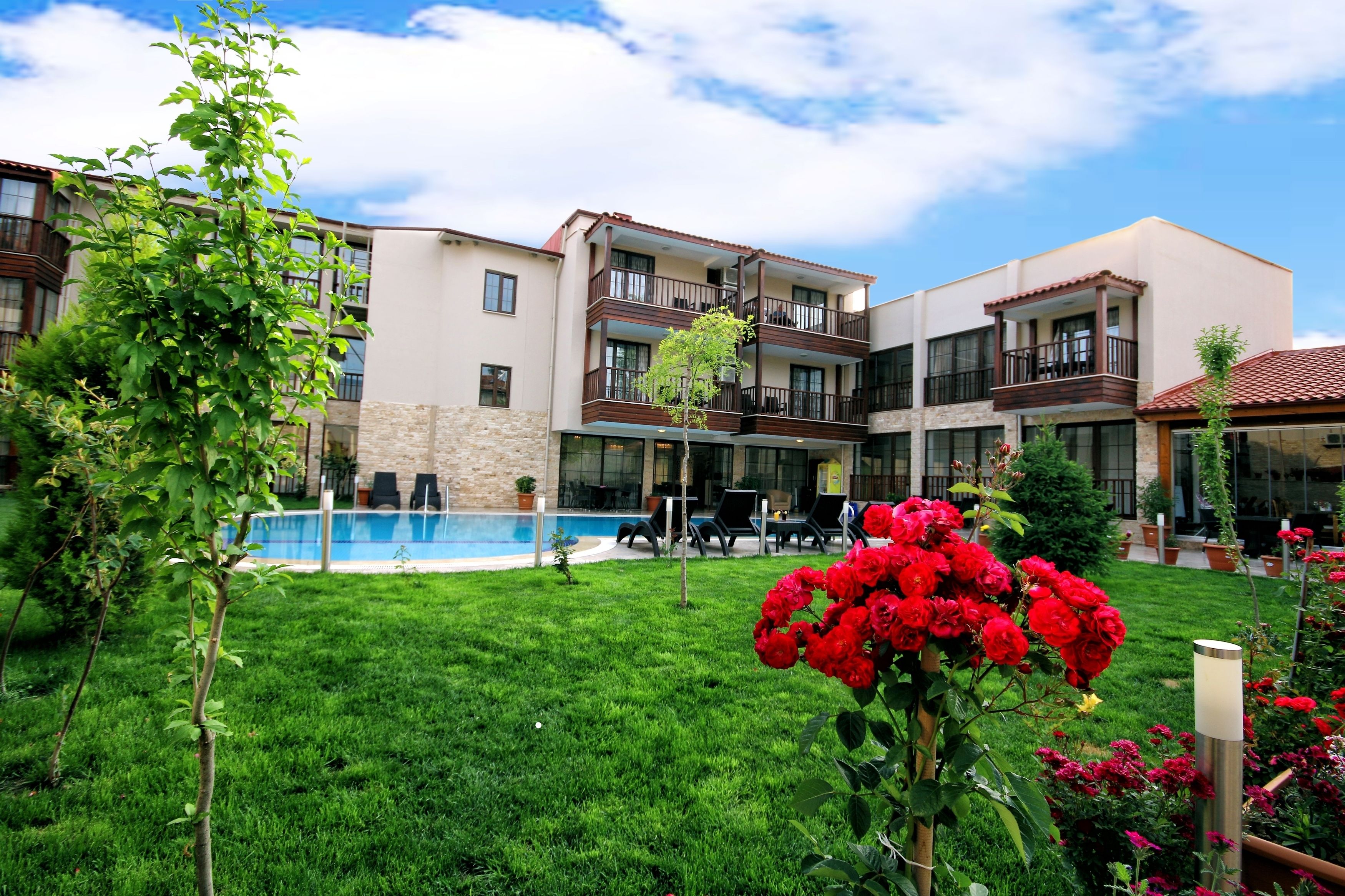 A hotel with a swimming pool, outdoor seating, and a well-maintained garden.