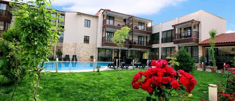 A hotel with a swimming pool, outdoor seating, and a well-maintained garden.