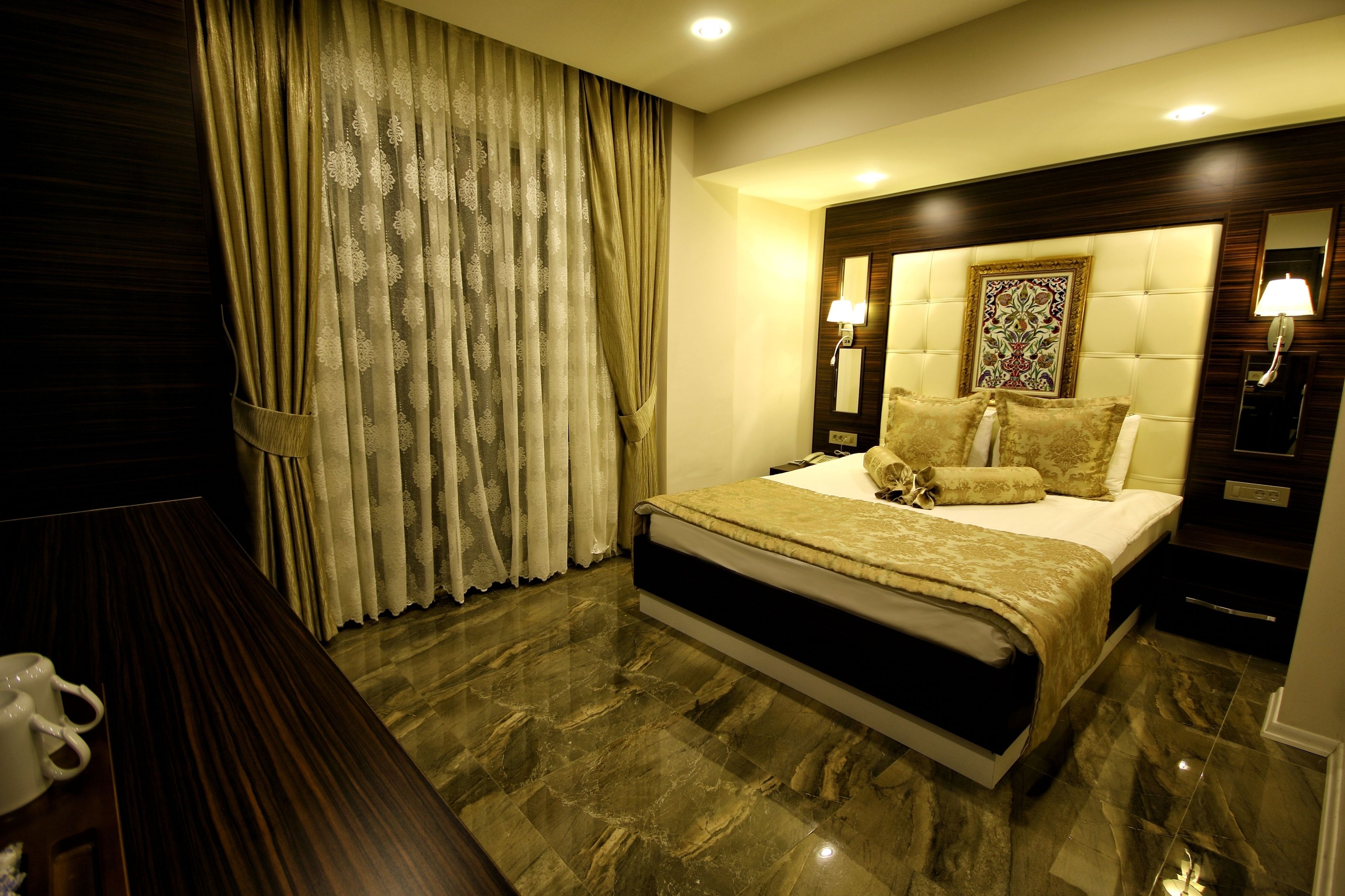 A modern bedroom with a large bed, a nightstand, a lamp, and a wall-mounted mirror.