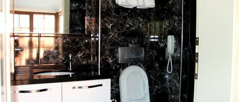 Un baño con lavamanos de mármol, inodoro y toallero.