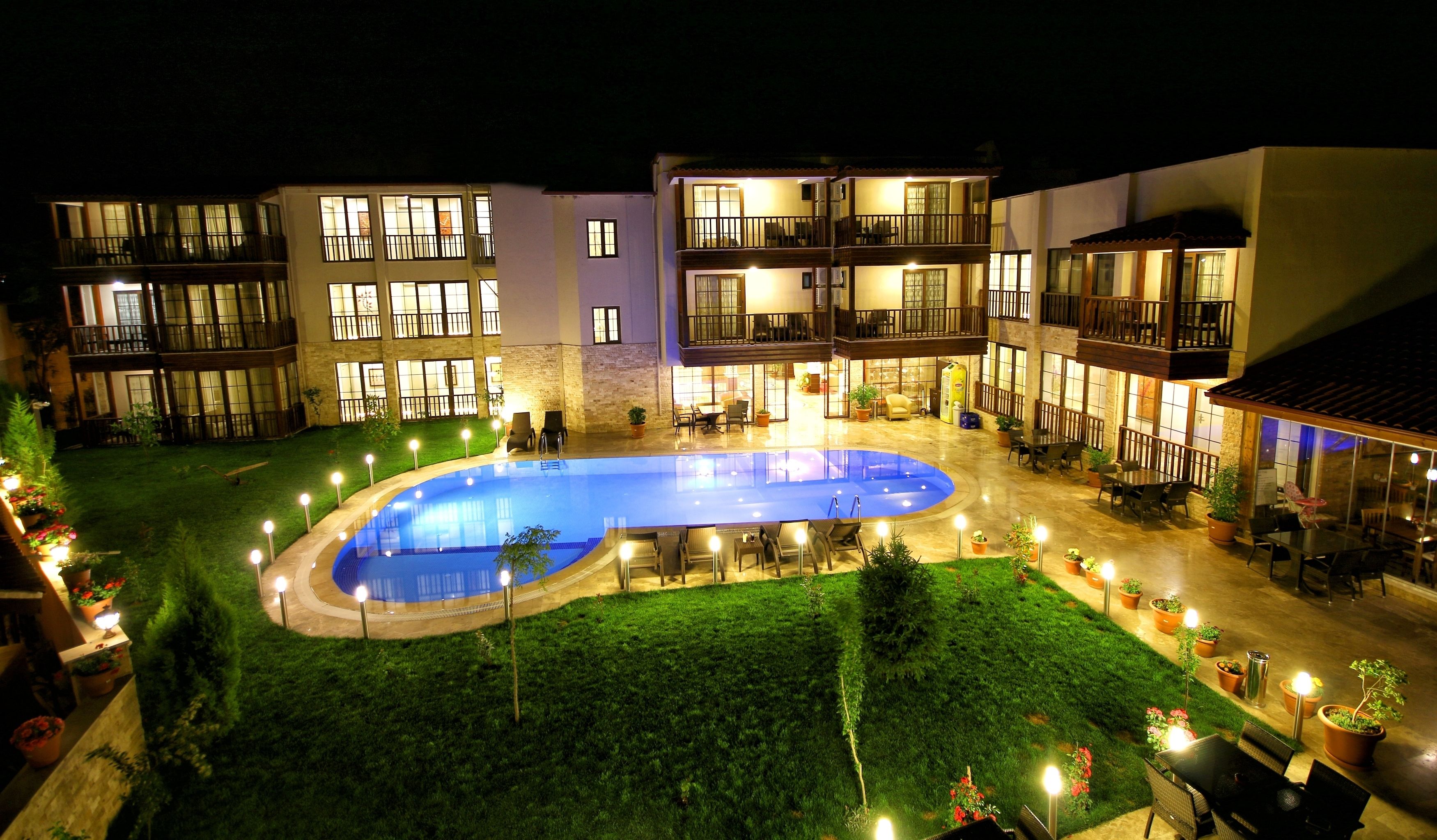 A hotel with a swimming pool surrounded by outdoor seating areas and a well-lit courtyard.