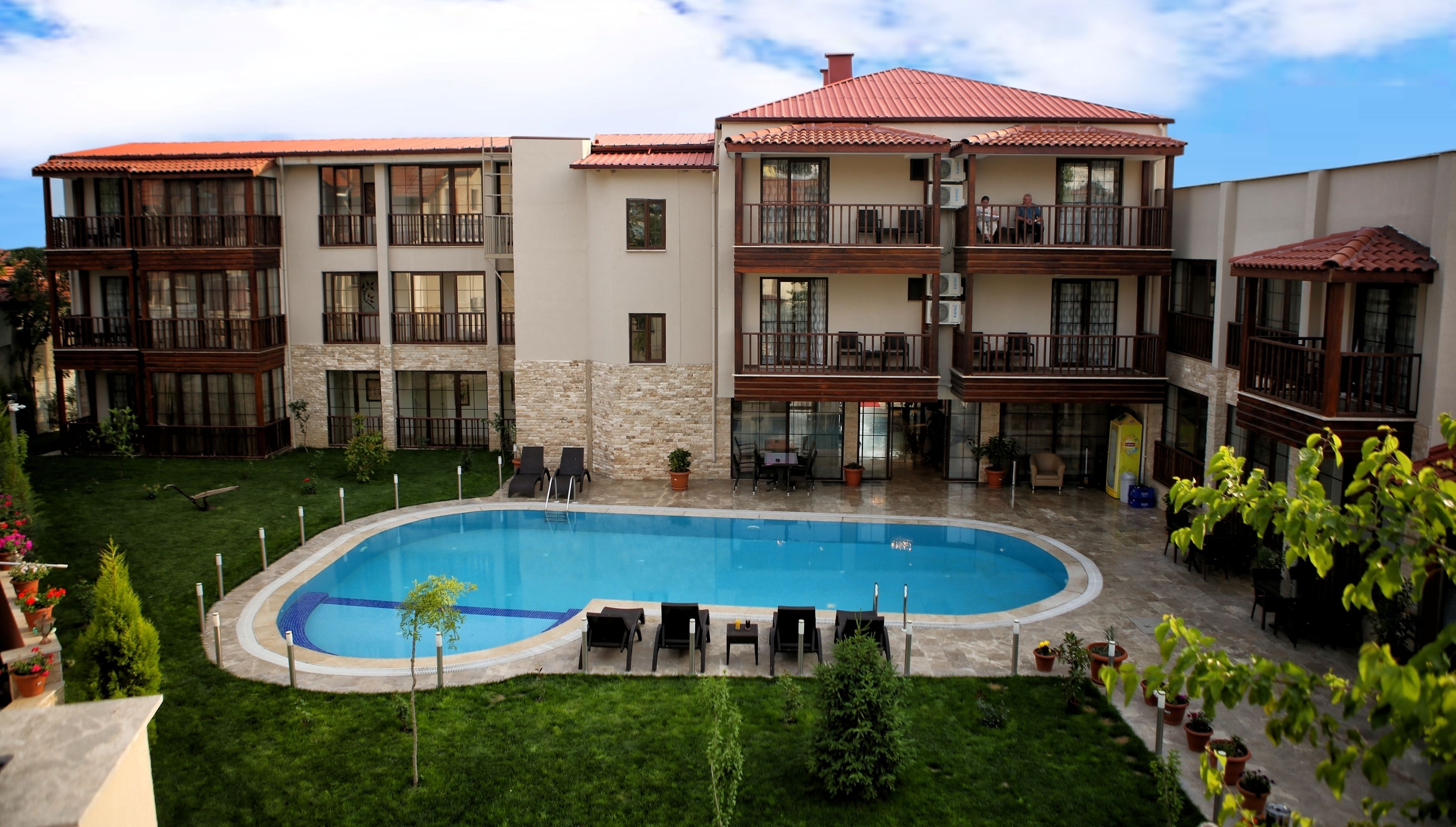 Um hotel com piscina, várias varandas e um jardim.