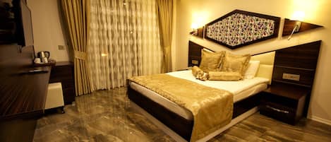 A hotel room with a large bed, a desk, a television, and a window with curtains.