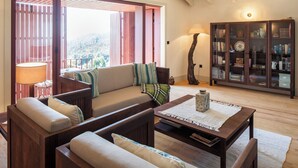 Un salon confortable avec un canapé, des fauteuils, une table basse et une bibliothèque.