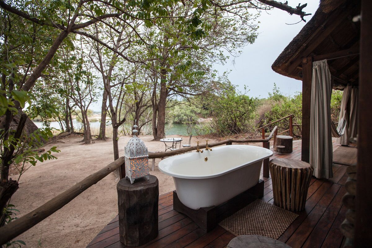 An outdoor wooden deck with a bathtub, a lantern, and a rustic wooden structure.