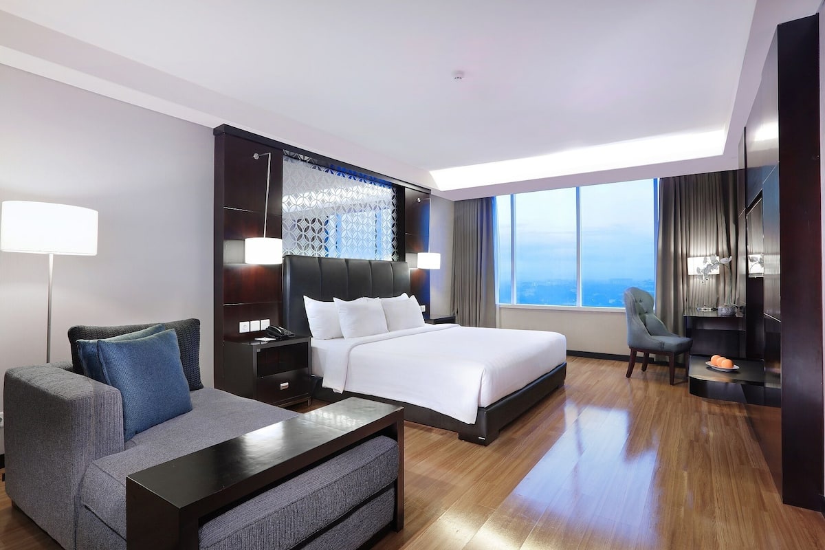 Une chambre d’hôtel moderne dotée d’un grand lit, d’un canapé, d’un bureau et offrant une vue sur la ville.