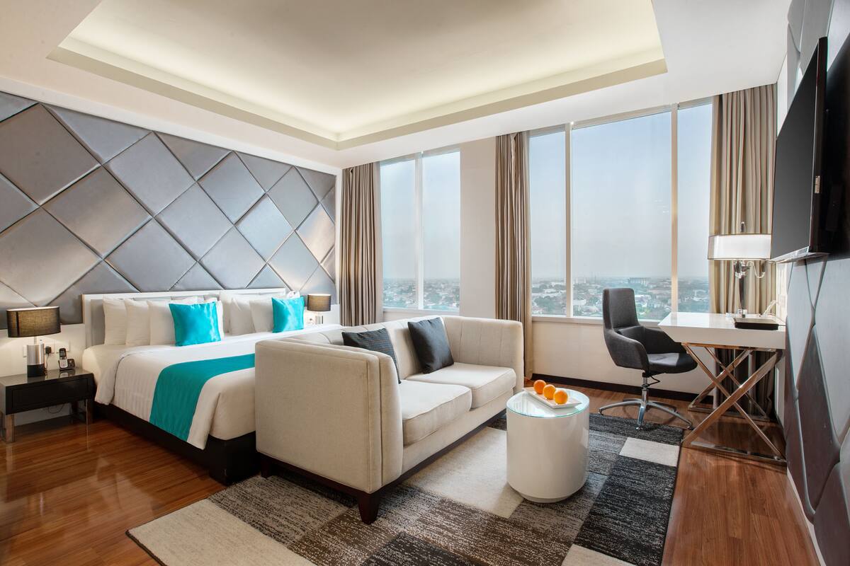 Une chambre d’hôtel moderne équipée d’un grand lit, d’un canapé, d’un bureau et d’une télévision.