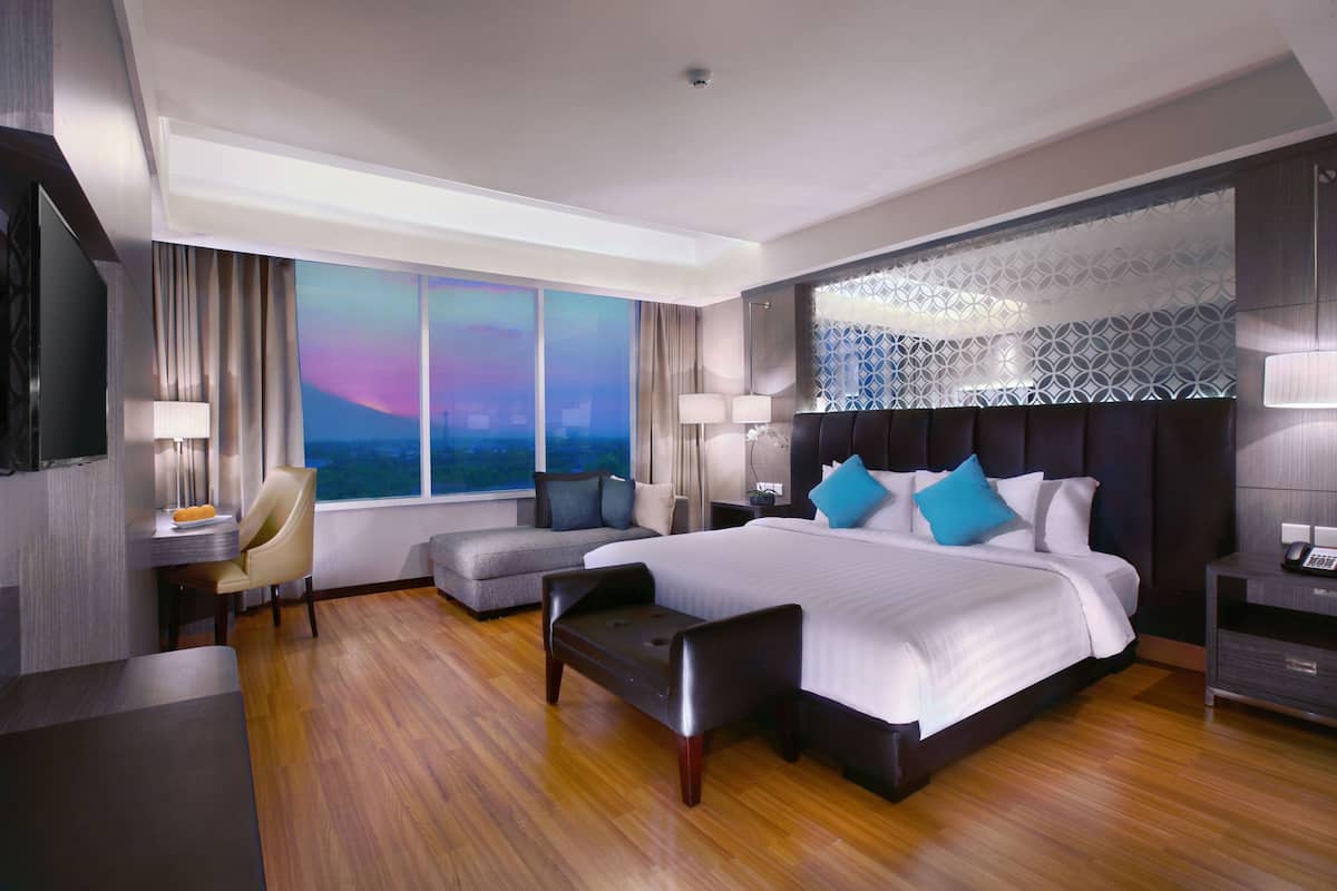 Une chambre d’hôtel moderne dotée d’un grand lit, d’un bureau, d’un canapé et offrant une vue sur le paysage urbain.