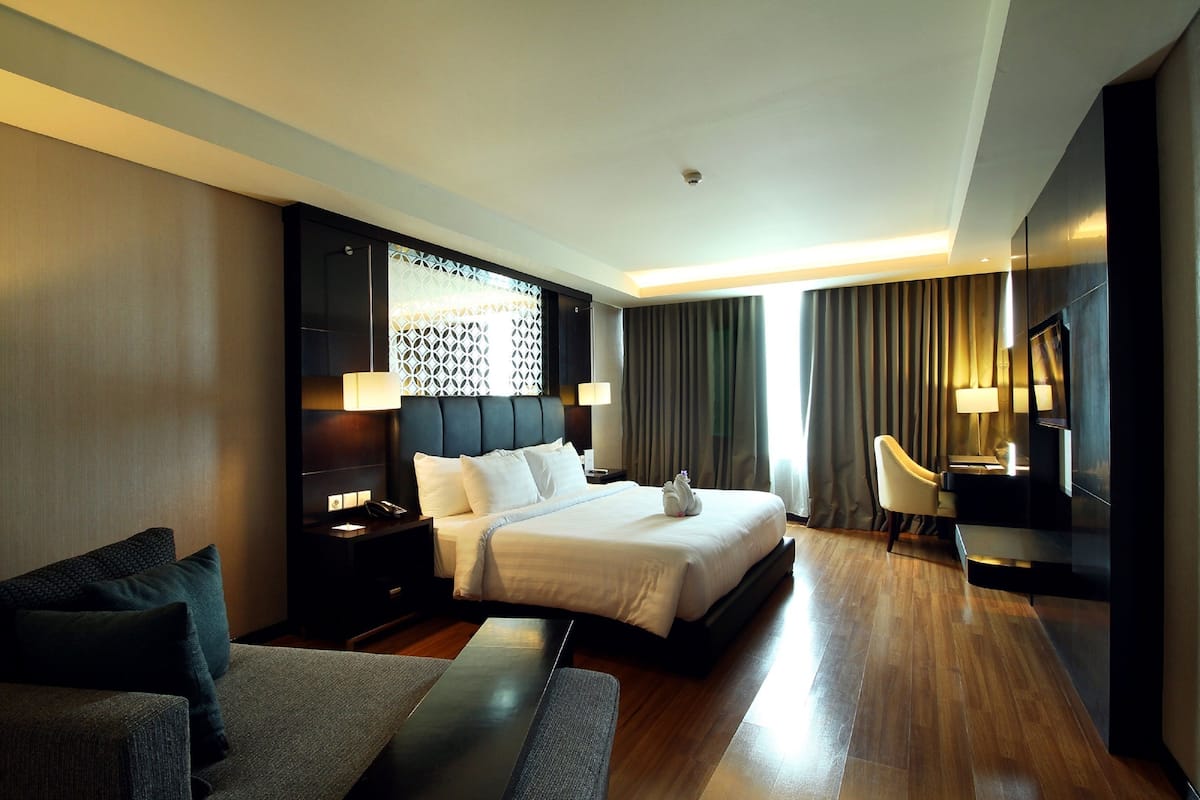 Une chambre d'hôtel moderne avec un grand lit, un bureau, une chaise, une télévision et un mur décoré de motifs.
