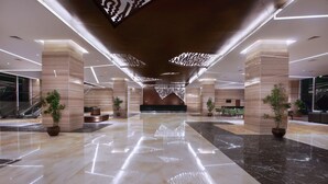 Un vestíbulo amplio con piso de mármol pulido, luminarias modernas y plantas en macetas.
