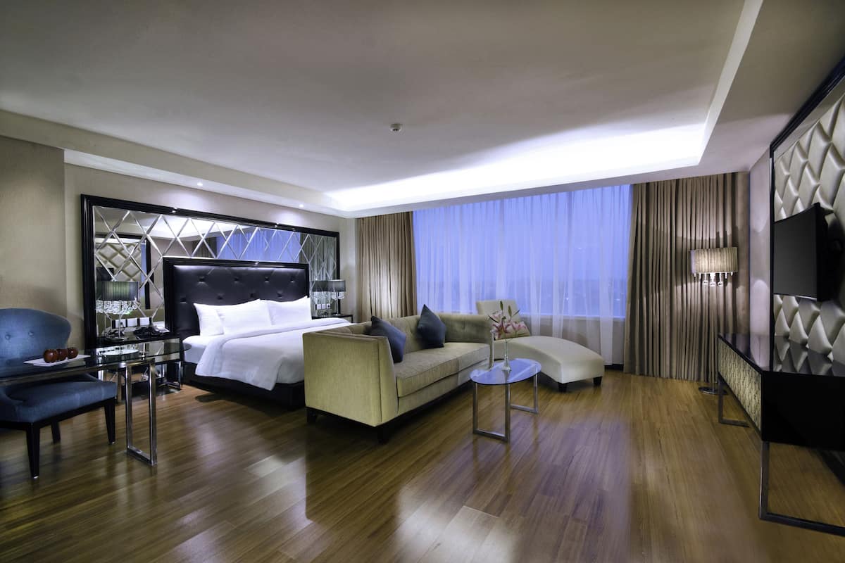 Une chambre d’hôtel moderne avec un grand lit, un canapé, une petite table et un téléviseur.