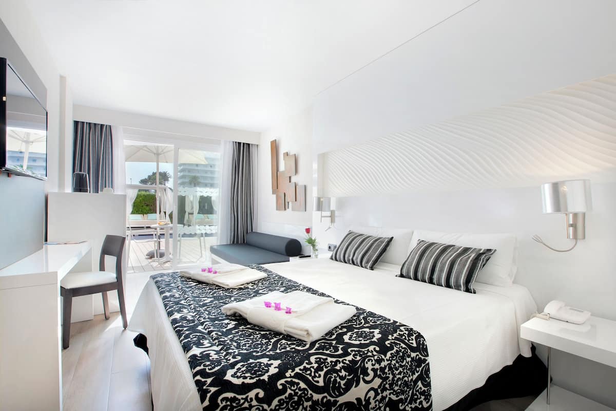 Una habitación de hotel moderna con una cama grande, un escritorio y vistas al exterior.