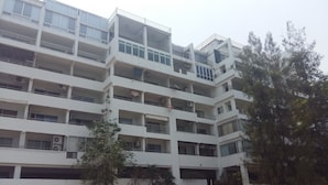 A multi-story building with balconies, air conditioning units, and a tree in the foreground. - Sammuk Resort (Chonburi)