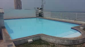 A rooftop swimming pool with a view of the city skyline. - Sammuk Resort (Chonburi)