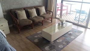 A living room with a sofa, a glass coffee table, and a patterned rug. - Sammuk Resort (Chonburi)