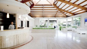 A spacious lobby with a high ceiling, a reception desk, and a seating area with a view of the outdoors. - Mar Hotels Playa Mar & Spa (Pollenca)