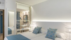 A modern hotel room with a large bed, a glass-enclosed shower, a white nightstand, and a mirror. - Mar Hotels Playa Mar & Spa (Pollenca)