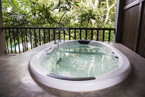 Ein Whirlpool auf einem Balkon mit Blick auf üppiges Grün.