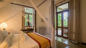 Ein Schlafzimmer mit Bett, Nachttisch, Lampe und Blick ins Freie.