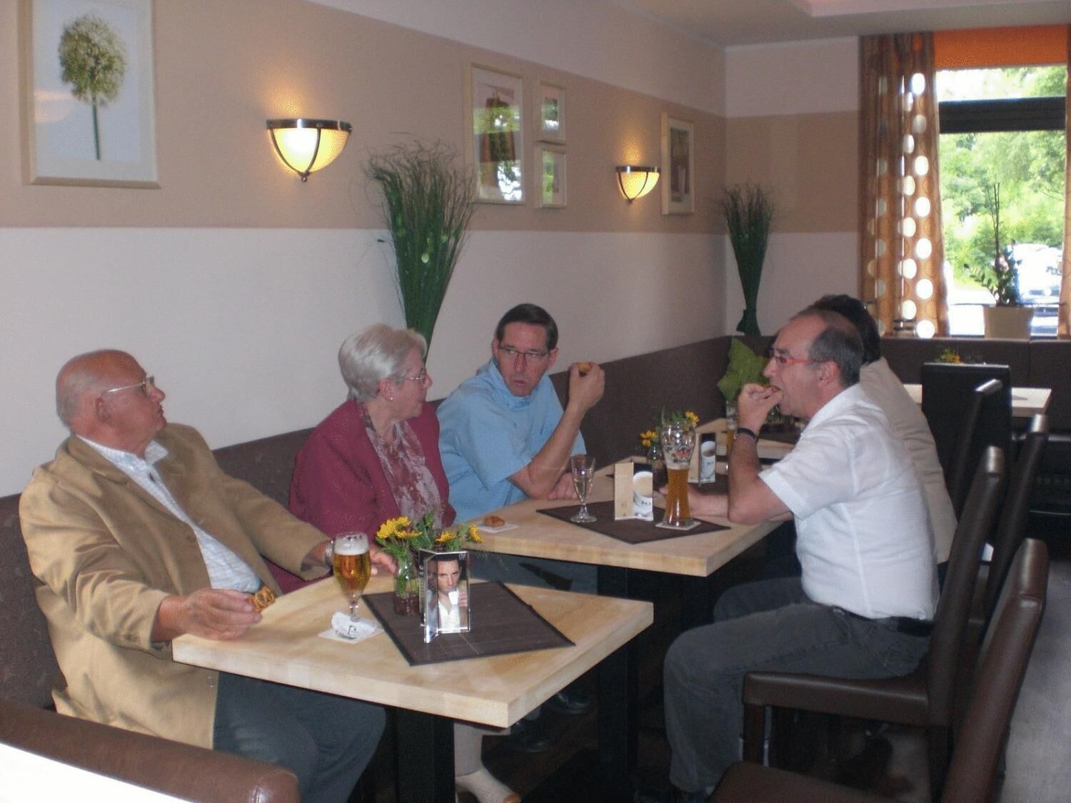 Un grupo de personas sentadas en una mesa en un restaurante, con luces fijadas en la pared y cuadros enmarcados.