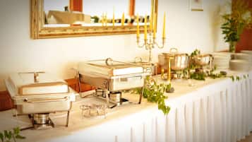 A buffet setup with multiple serving stations, a mirror, and candle holders on a white tablecloth.
