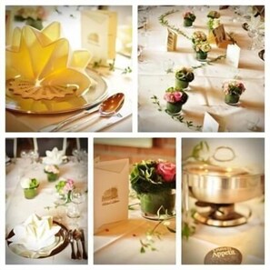 A table setting with a yellow floral centerpiece, small potted plants, and a silver bowl with the word "Appetit". - Hotel Litjes (Goch)