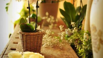 Ein Korbkörbchen mit weißen Blumen, einer grünen Pflanze und einer Speisenplatte auf einem Holztisch.