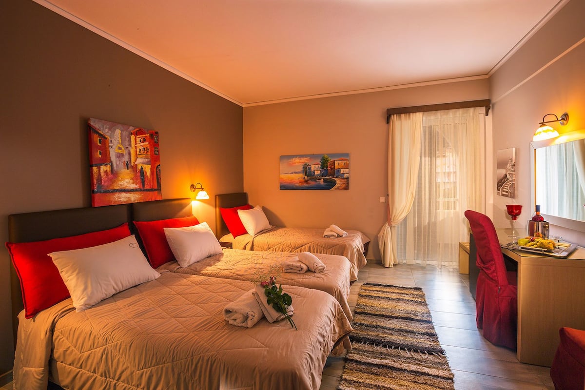 A hotel room with two beds, a desk, a chair, and artwork on the walls.