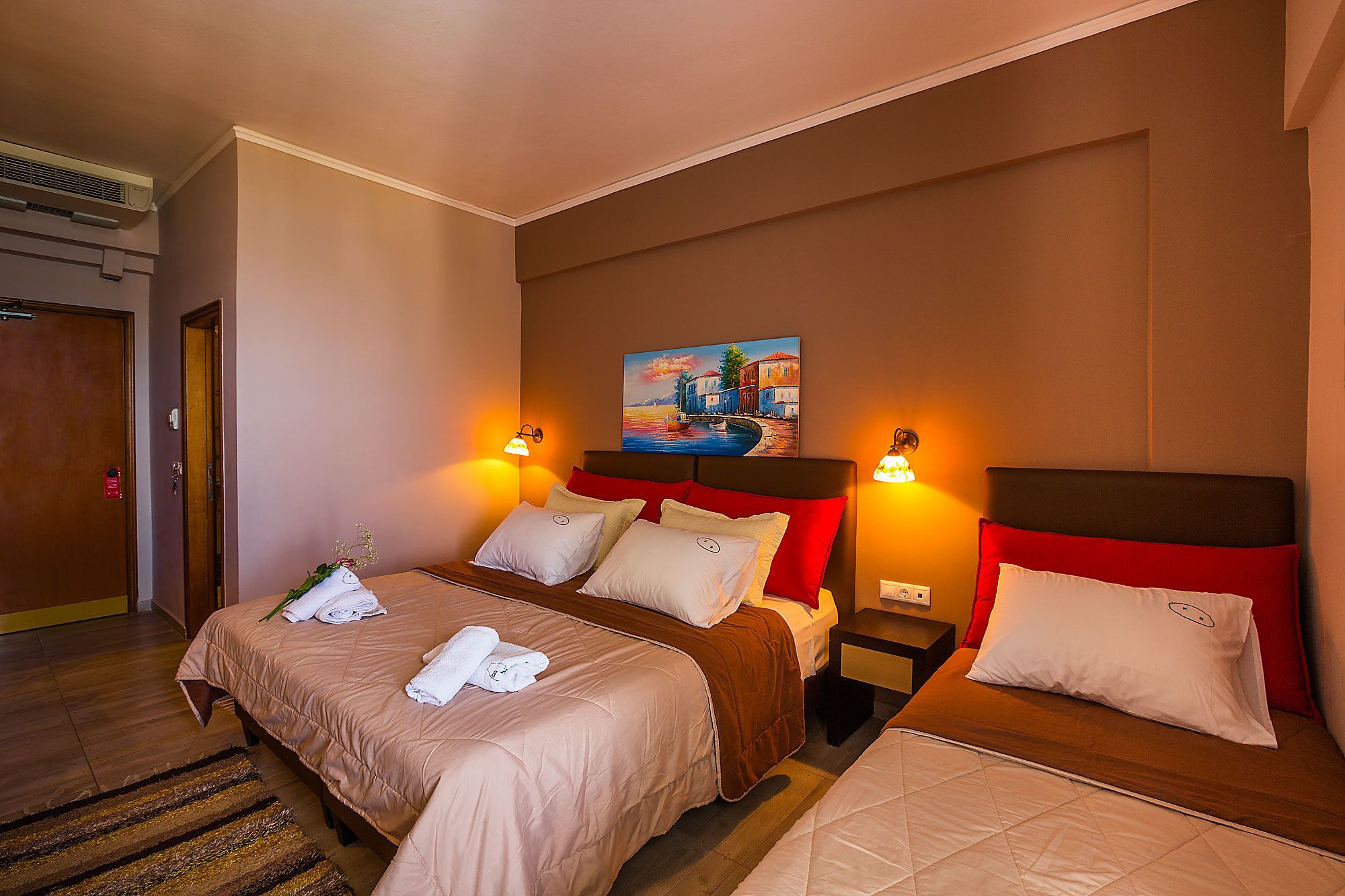 Une chambre d’hôtel avec deux lits, un tableau au mur et deux lampes fixées au mur.