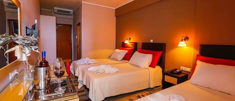 A hotel room with two beds, a minibar, a mirror, and a bathroom visible in the background.