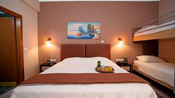 Una habitación de hotel con una cama grande, una cama nido más pequeña, dos mesitas de noche con lámparas, un cuadro en la pared y una bandeja con alimentos para el desayuno.