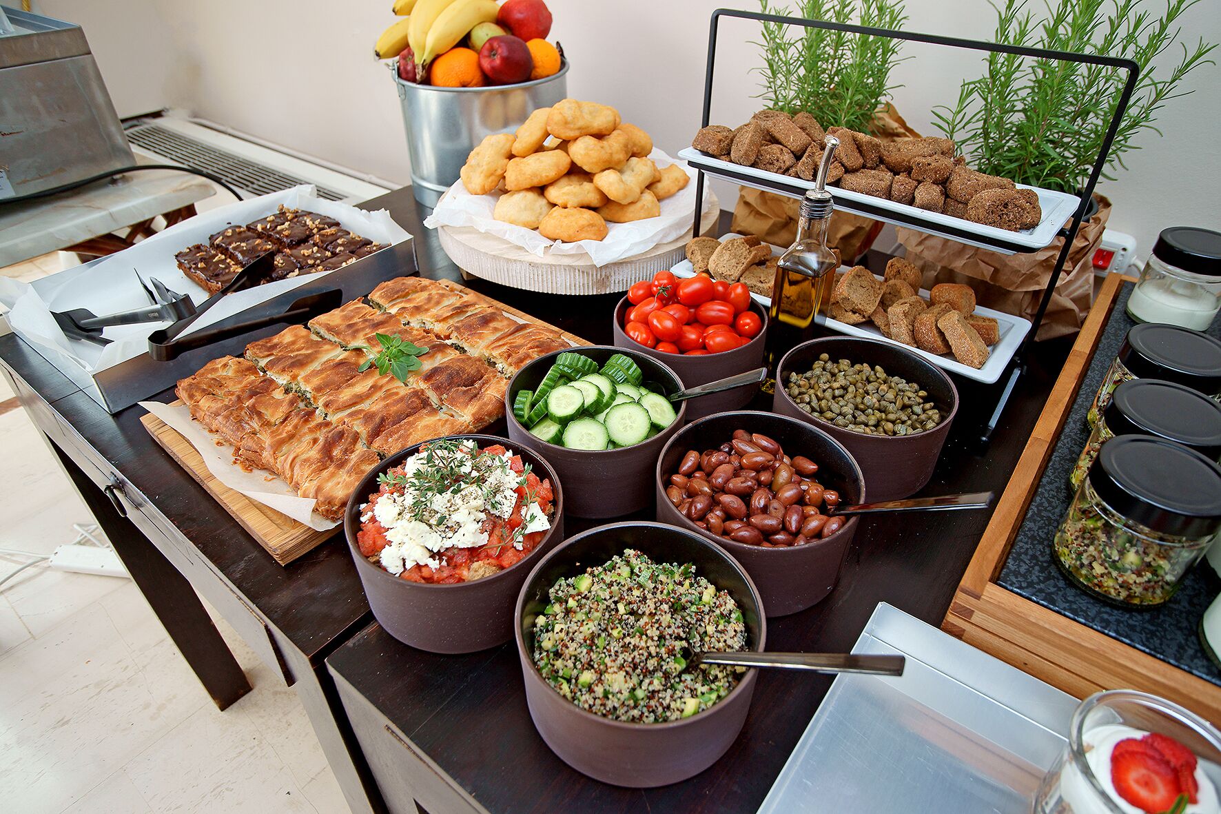 Un buffet proposant une variété de plats, notamment des pâtisseries, des fruits, des légumes et des salades.