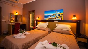 Habitación de hotel con dos camas, un cuadro de paisaje costero, un equipo de aire acondicionado, un espejo y una mesita de noche con una lámpara.
