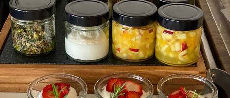 A display of food items, including jars with various contents and small glass containers with layered desserts.