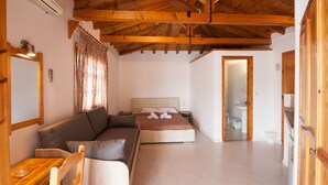 A room with a wooden ceiling, a bed, a sofa, a small table, and a mirror. - Pension Eliza (Skiathos)