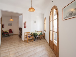A dining area with a table and chairs, a fire extinguisher on the wall, and a large window with a view. - Pension Eliza (Skiathos)